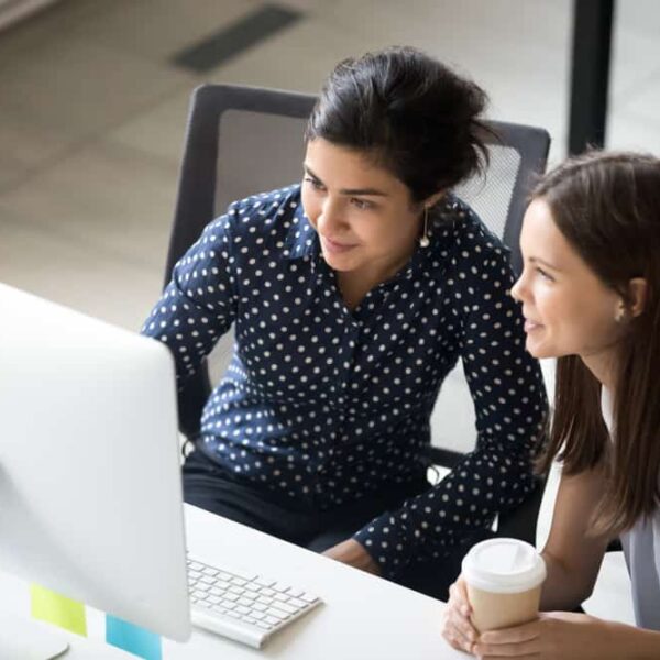 two women looking at computer at desk