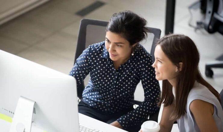 two women looking at computer at desk